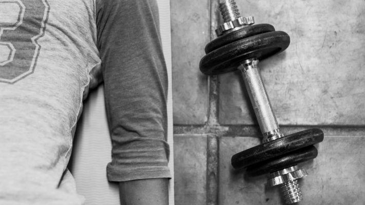 person in black pants and black socks holding dumbbell